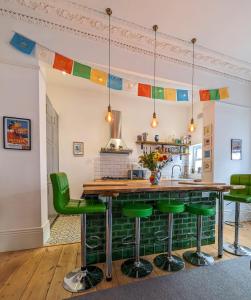 una cocina con barra con taburetes de bar verde en Church Retreat - A Magnificent Sea Side Apartment, en Hastings