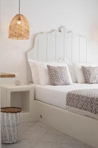 białe łóżko z białymi poduszkami i koszem w obiekcie Aeolos Villas Sustainable Living w mieście Agkidia