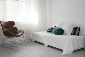 a white bedroom with a bed and a chair at Landhaus Refugium in Weissach
