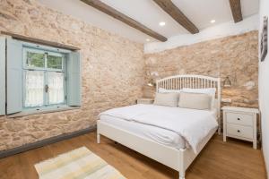 a bedroom with a white bed and a stone wall at Villa Ivka in Tribalj