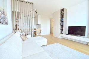 a white living room with a white couch and a television at Downtown Charm with free parking spot in Bratislava