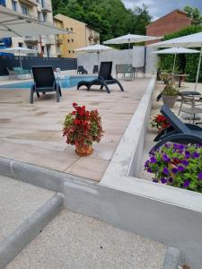 - une terrasse avec 2 chaises et des fleurs à côté de la piscine dans l'établissement Logis hôtel restaurant les Carillons, à Cransac