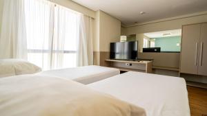 a hotel room with two beds and a flat screen tv at Roomo Praia de Boa Viagem Residencial in Recife