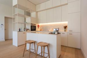 a kitchen with white cabinets and two bar stools at Mouzinho 32 in Porto