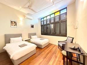 Zimmer mit 2 Betten, einem Schreibtisch und einem Fenster in der Unterkunft Madras Inn 58-1 in George Town