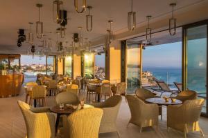 a restaurant with tables and chairs and windows at EVOLUTION Cascais-Estoril Hotel in Estoril