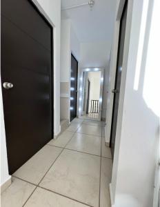 a hallway with a black door and a tile floor at Casa valle oriente in Saltillo