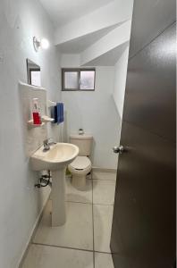 a white bathroom with a toilet and a sink at Casa valle oriente in Saltillo