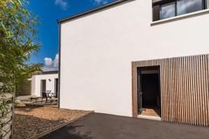 een wit huis met een houten deur aan de zijkant bij Maison de vacances à Pordic - proche de la mer in Pordic