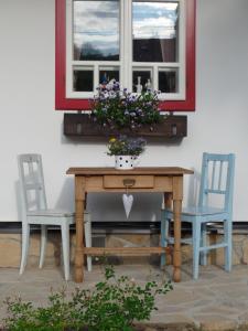 einen Tisch mit 2 Stühlen und ein Fenster mit Blumen in der Unterkunft Penzion Roubenka in Hukvaldy