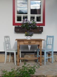 una mesa con 2 sillas y una ventana con flores en Penzion Roubenka, en Hukvaldy