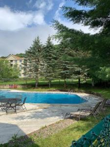 a swimming pool with a table and chairs in a yard at Mountainside Condo @ Jiminy Peak in the Berkshires in Hancock