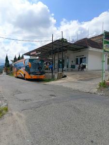 PadangluarにあるMutiara Guest House Syariahのオレンジバスが停車している