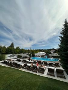 Eine Gruppe von Menschen sitzt auf Stühlen neben einem Pool in der Unterkunft Grigliata Motel and Pool in Glevakha