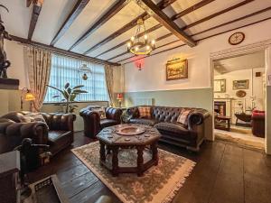 uma sala de estar com sofás de couro e uma mesa em Moulsham House em Stoke Ferry