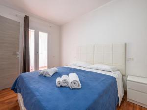 - une chambre blanche avec un lit bleu et des serviettes dans l'établissement CASA FIORI, à Cagliari