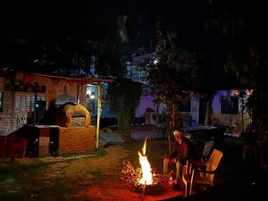 a person sitting around a fire in a yard at night at Baba hostel in Pushkar
