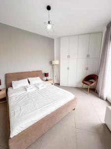 een witte slaapkamer met een groot bed en een stoel bij Gladiolus ANhome Premium Selections in Athene