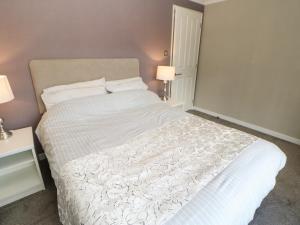 um quarto com uma grande cama branca e 2 candeeiros em Emmerdale Lodge em Yarm