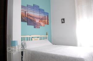una camera da letto con un letto e un dipinto sul muro di Apartamento San Juan de Dios a Siviglia