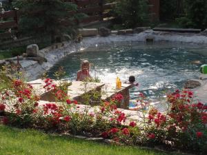 two children playing in a swimming pool in a yard at Penzion Roubenka in Hukvaldy
