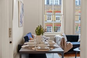 Delightful Flat in London - Sleeps 6 في لندن: غرفة طعام مع طاولة مع أطباق عليها
