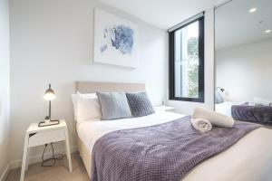 Habitación blanca con cama y ventana en Stunning 2br2ba Apt North Melwi-fifree Parking en Melbourne