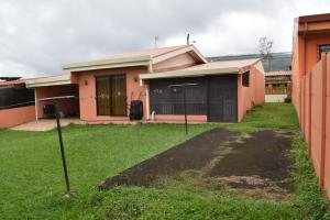 una casa con un patio de hierba delante de ella en SERENITY HOME H Y M en Turrialba