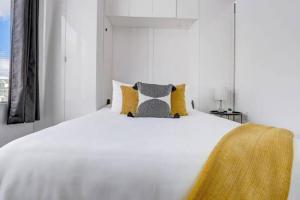 um quarto branco com uma cama branca com almofadas amarelas em KCM Tremont Oaks Apartments 7 em Cleveland