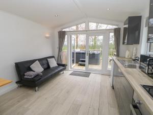 a living room with a black couch and a kitchen at Roseberry Pod in Yarm