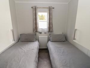 twee bedden in een kleine kamer met een raam bij Swaledale Large Pod in Yarm