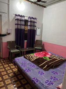 a bedroom with a bed and two chairs and a table at Baba hostel in Pushkar