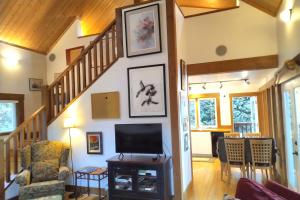 a living room with a staircase and a flat screen tv at Moon Dance Cabin in Madeira Park