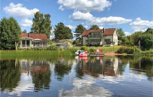 a house on a lake with a boat in the water at Lovely Home In Hjltevad With House Sea View in Hjältevad