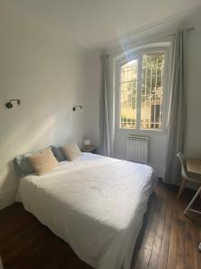 a bedroom with a large white bed and a window at Kak's apartments Paris in Paris
