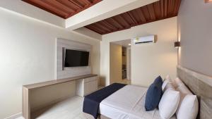 1 dormitorio con 1 cama y TV en la pared en On Vacation Caribbean, en San Andrés