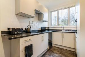 a kitchen with white cabinets and a sink at 4 bedroom Home close to the City Centre in Nottingham