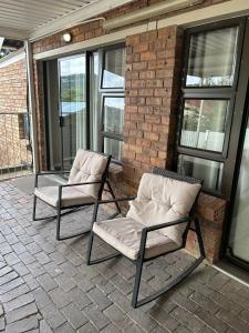 two chairs sitting on a patio next to a brick wall at Hillsview, Roodepoort in Roodepoort