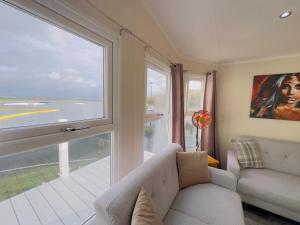 a living room with a couch and a large window at LakeDistrict Caravan by Sleepy in Millom