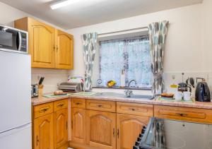 a kitchen with wooden cabinets and a sink and a window at The Carriage House Upcott House in Barnstaple