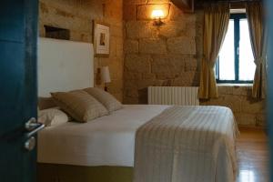 een slaapkamer met een bed in een bakstenen muur bij Casa Rural Rectoral de Armariz in Nogueira de Ramuin