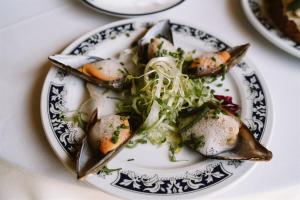 a plate of food with oysters and vegetables on a table at Casa Rural Rectoral de Armariz in Nogueira de Ramuin