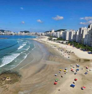 Apartamento Alto Padrão في غوارويا: شاطئ به مجموعة من المظلات والناس