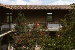 dom z drzewem z czerwonymi kwiatami przed nim w obiekcie Casa Rural Rectoral de Armariz w mieście Nogueira de Ramuin