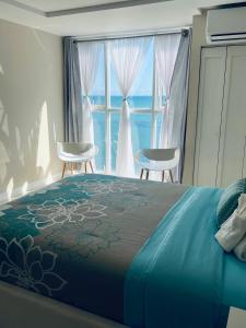 a bedroom with a bed with two chairs and a window at Large Luxurious Beach Front 1 Bedroom at Bayfront Villa in Portmore