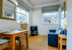 a living room with a table and a blue couch at The Mews in Southwold