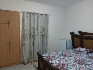 a bedroom with a bed and a curtain with trees at VACATION HOME STAY AT SHRJAH DUBAI BORDER By mauon tourism in Sharjah