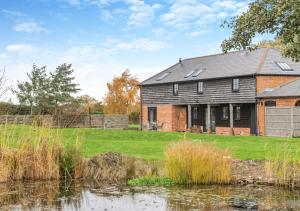 a brick house next to a body of water at Plough Cottage in Yoxford