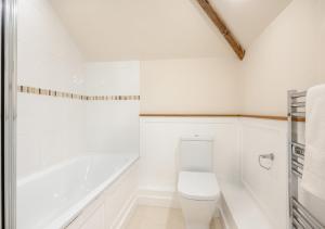 a white bathroom with a toilet and a bath tub at Plough Cottage in Yoxford
