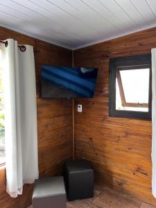 Habitación con pared, TV y ventana. en Tombo Beach Hostel & Pousada, en Guarujá